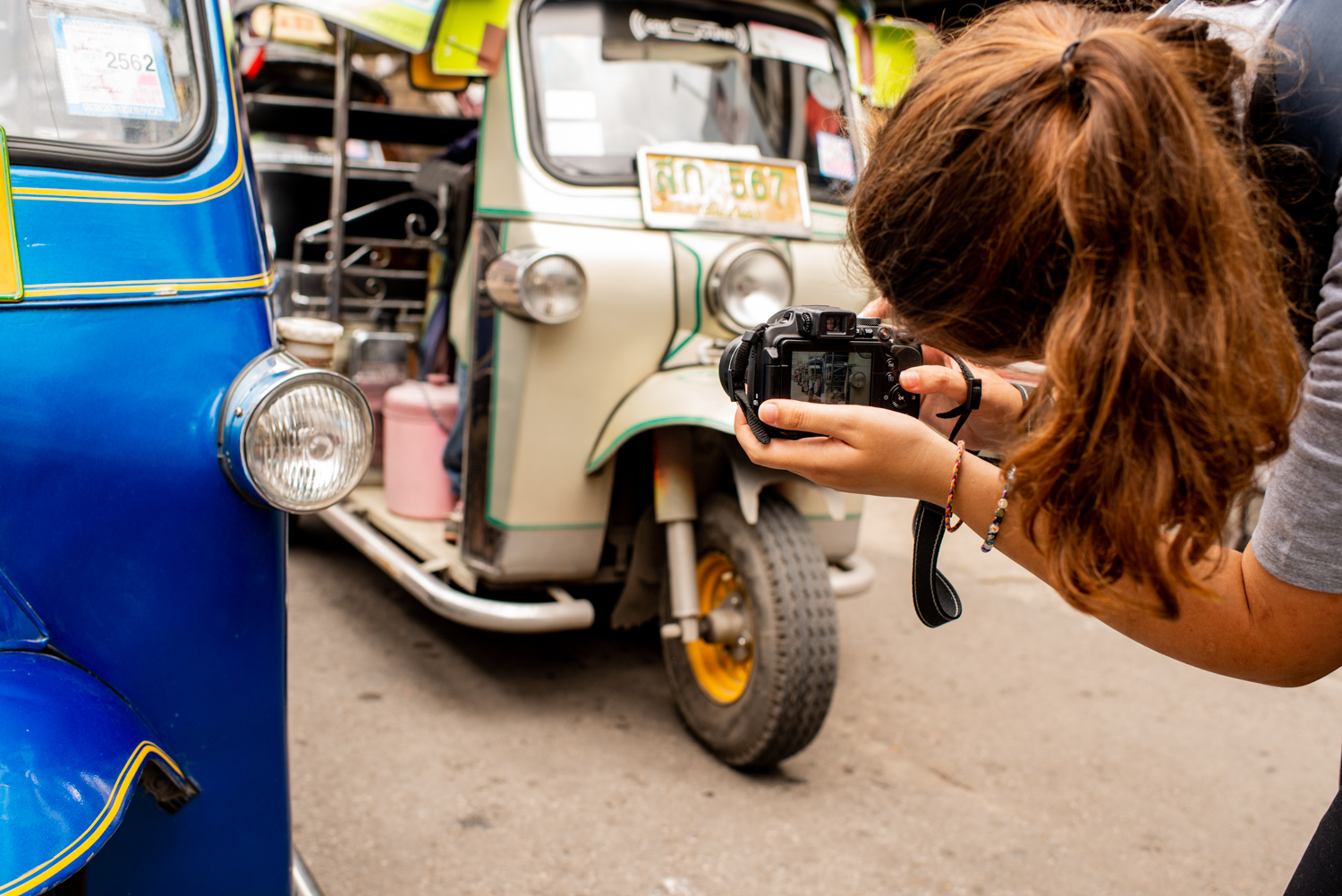 Young woman taking a photograph of tuk tuks