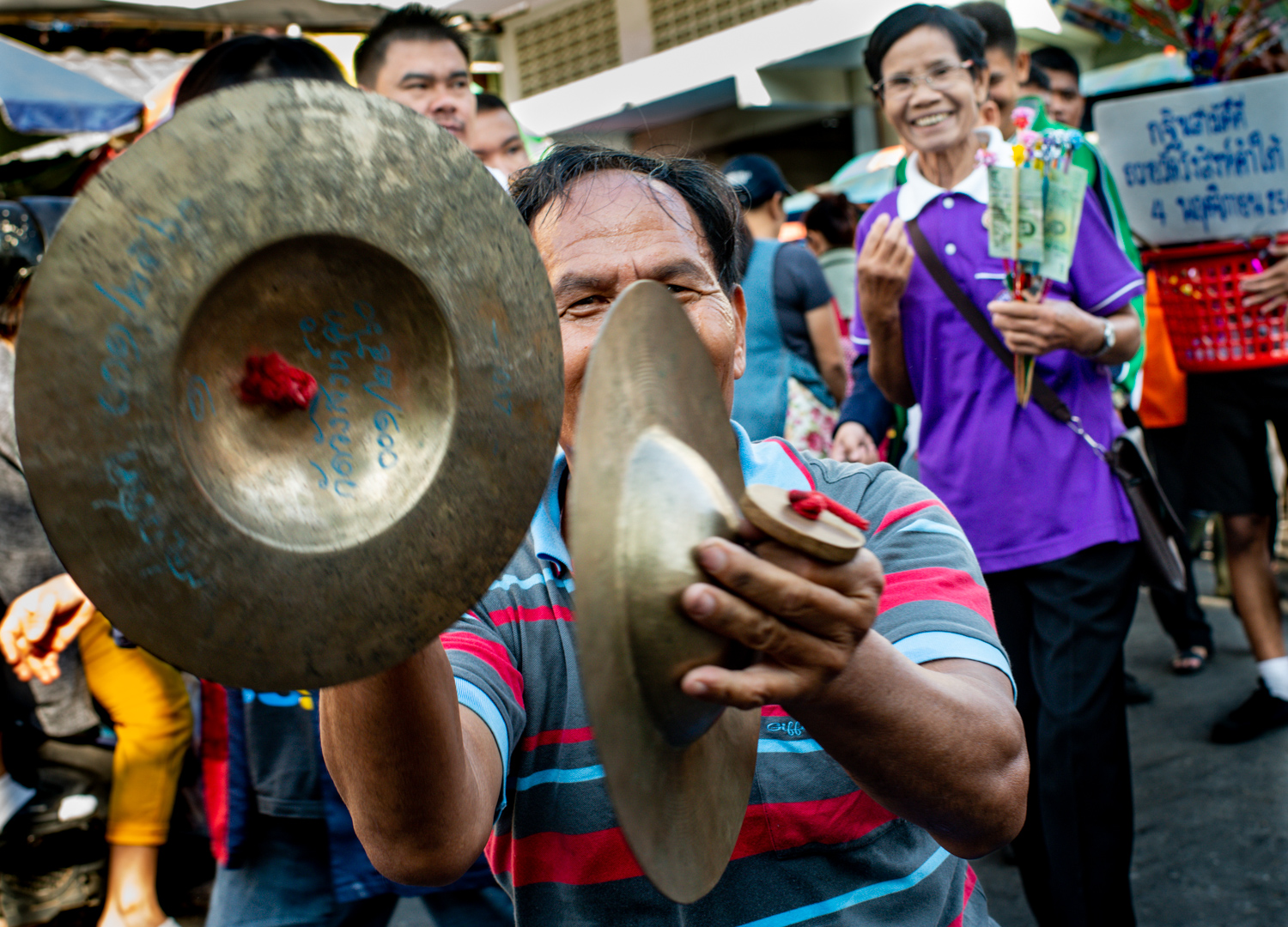 Man playing a pair of hand cymbols in a street market in Chiang Mai, Thailand