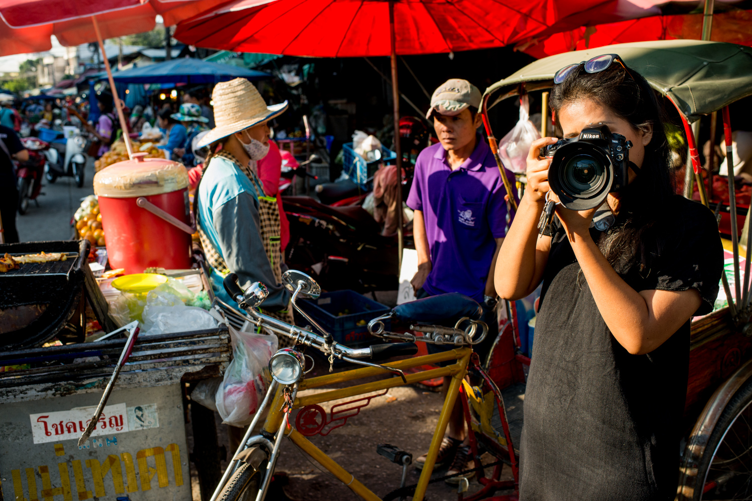 Asian woman taking a photograph at a street market.