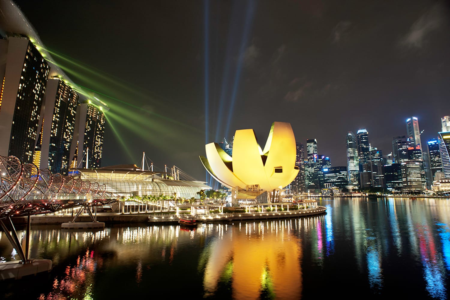 Marina Bay Sands Hotel and the ArtScience Museum during an evening light show with the CBD of Singapore in the background.